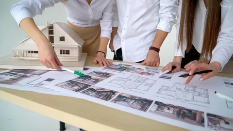 Close Up Of four Architects Discussing Plan Together At Desk With Blueprints Stock Footage 88597367