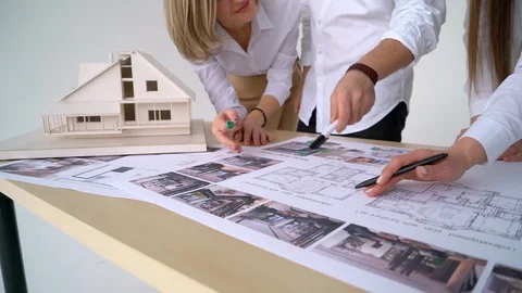 Close Up Of four Architects Discussing Plan Together At Desk With Blueprints Stock Footage 88598142