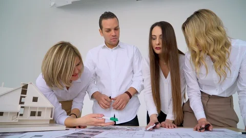 Close Up Of four Architects Discussing Plan Together At Desk With Blueprints Stock Footage 88600784