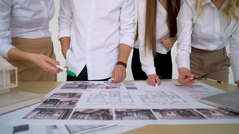 Close Up Of four Architects Discussing Plan Together At Desk With Blueprints Stock Footage 88603781