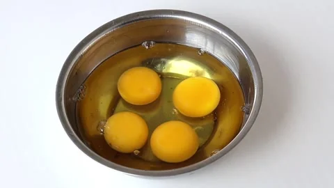 Close-up of four bright yellow egg yolks in a stainless steel bowl for baking. Stock Footage 320588134