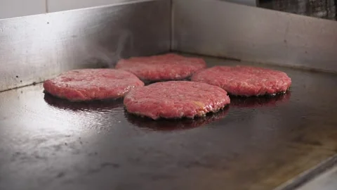 Close-up of four burger patties fried on a hot industrial stove in the kitchen. Stock Footage 342702378