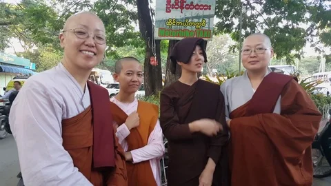 Close up of four Burmese robed buddhist nuns, motorbike taxi sign, Mandalay Видео 79627280