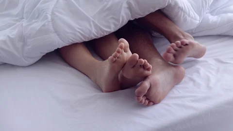 Close-up four feet on the bed under the white blanket. Видео 107736194