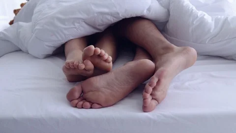 Close-up four feet on the bed under the white blanket. Видео 107736702