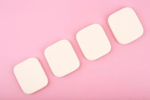 Close up of four make up sponges in diagonal row on bright pink background Stock Photos