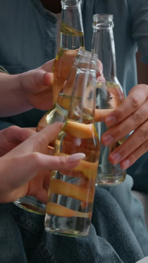 Close up four unrecognizable friends clinking bottles at home part drinking beer Stock Footage 319077493