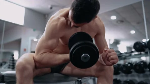 The close frame of the athlete performing, sitting, lifting the dumbbell with Video stock 156477181