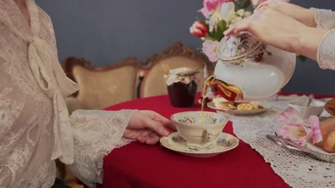 Close up frame of a vintage mug on a red tablecloth which is slowly filled with Stock Footage 145040937