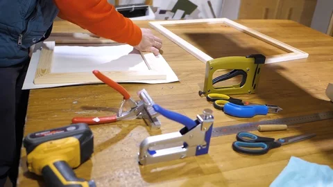 Close-up. Framing Workshop. A man stretches the canvass on wooden frame 스톡 동영상 128739652