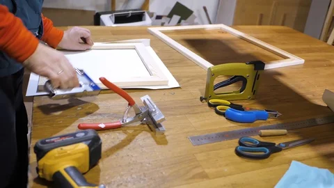 Close-up. Framing Workshop. A man stretches the canvass on wooden frame Stock Footage 128739690