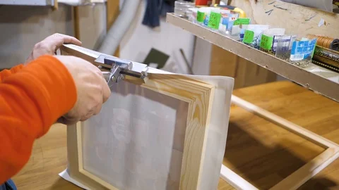 Close-up. Framing Workshop. A man stretches the canvass on wooden frame Stock Footage 128739797