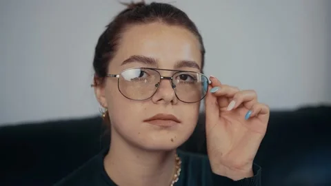 Close-up of the freckled, red-haired young woman with glasses holding her hand Video stock 160158011