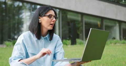Close up of freelance designer sitting cross-legged on the grass with headphones Stock Footage 317910257