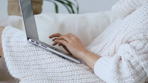 Close-up freelancer in home clothes on sofa actively work on laptop. Fingers Stock Footage 279752308