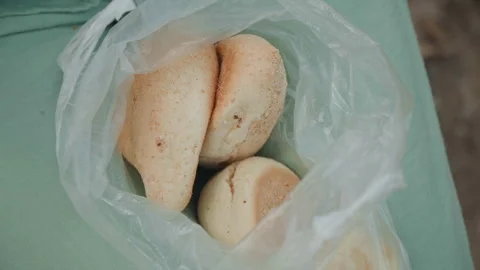 Close up of fresh baked rolls in plastic bag on green fabric with soft lighting Stock Footage 345043855