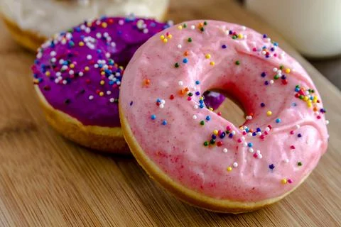 Close up of fresh baked vanilla bean doughnuts with colorful icing sitting .. Stock Photos