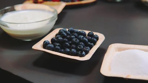 Close-up of fresh blueberries and baking ingredients on dark kitchen surface Vidéo 342839829