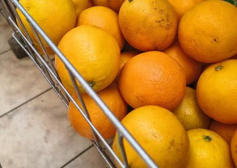 Close up of fresh bright oranges in a wire basket at the market. Stock Photos