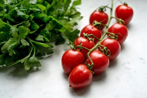 Close up of Fresh cherry tomatoes with bunch of parsley on a marble backgroun Stock Photos