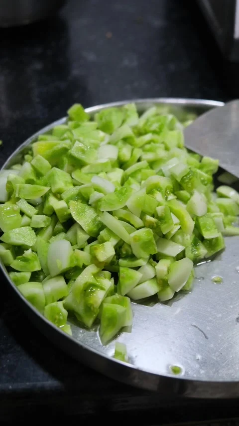 Close up of fresh chopped green tomatoes in steel plate on kitchen counter Video stock 331898838