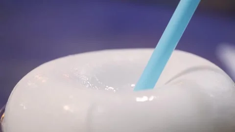 Close-up of Fresh Coconut Drink with Blue Straw Stock Footage 345650371