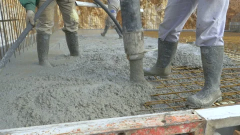 CLOSE UP: Fresh concrete flows out of a wide hose as contractors pour a slab. Stock Footage 137545855