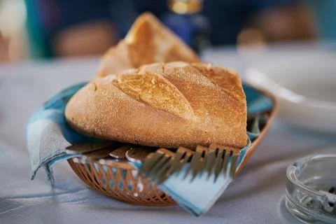 Close-up of fresh crusty bread served in a small basket with cutlery on a tab Stock Photos