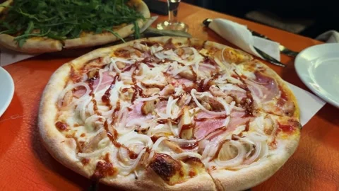 A close-up fresh delicious pizza with ham and onion. Appetizing recipe, Italian Stock Footage 321944062