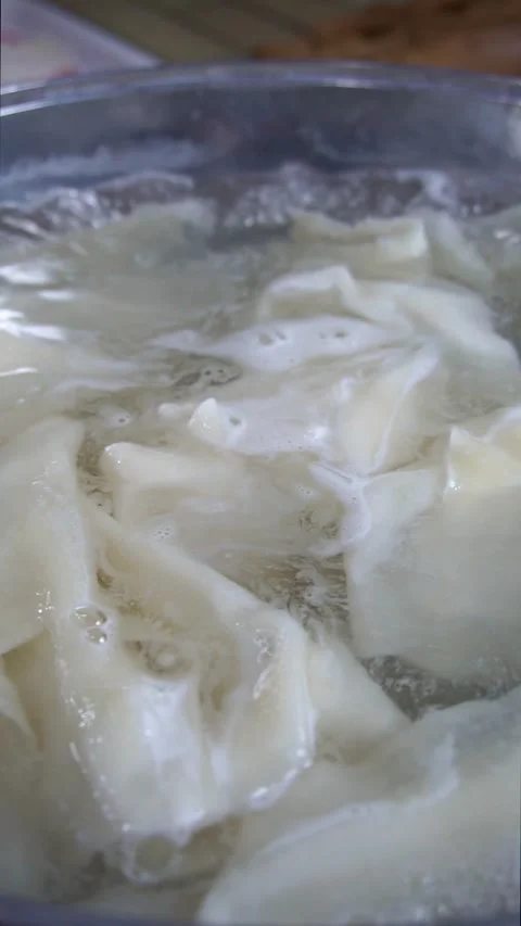 Close-up of fresh dough sheets boiling in hot water inside a metal pot for tradi Stock Footage 342627736