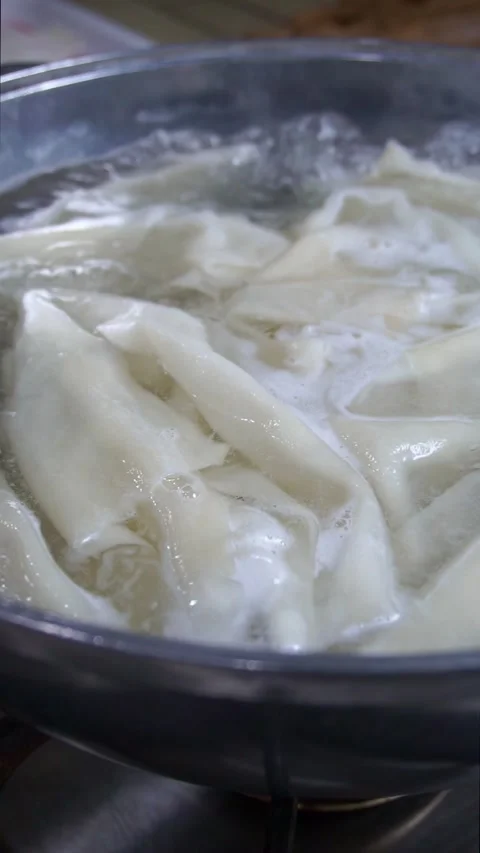 Close-up of fresh dough sheets boiling in hot water inside a metal pot for tradi Stock Footage 342627778