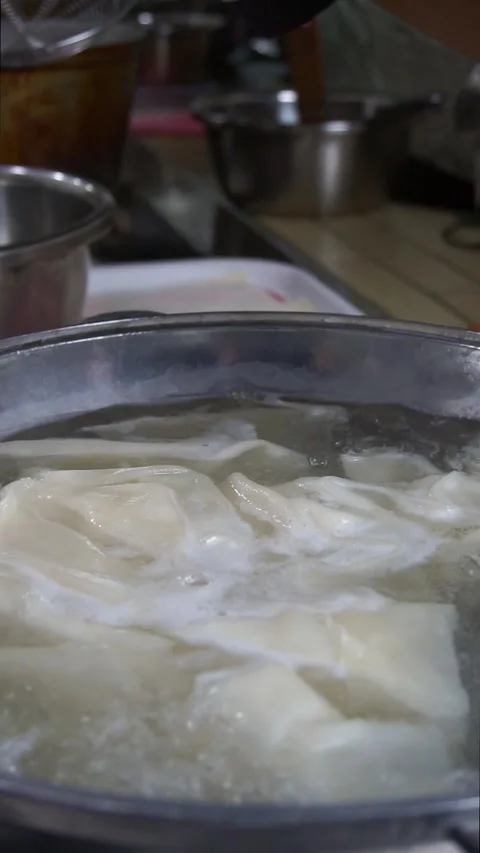 Close-up of fresh dough sheets boiling in hot water inside a metal pot for tradi Stock Footage 342627823
