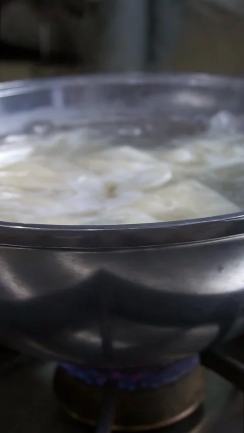 Close-up of fresh dough sheets boiling in hot water inside a metal pot for tradi Stock Footage 342627843