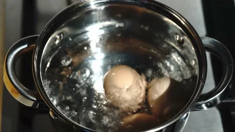 Close up of fresh farm eggs boiling in pot with hot water. Brown chicken egg for Stock Footage 134699378