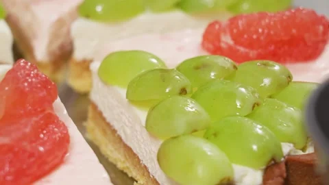 Close up of fresh fruit tart with green grapes and grapefruit segments being gla Stock Footage 337751307