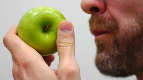 Close-up of a fresh green apple in the hand of a man biting it Stock Footage 329862380