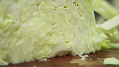 Close up of a fresh green cabbage being chopped with a knife on a wooden surface Stock Footage 340609131