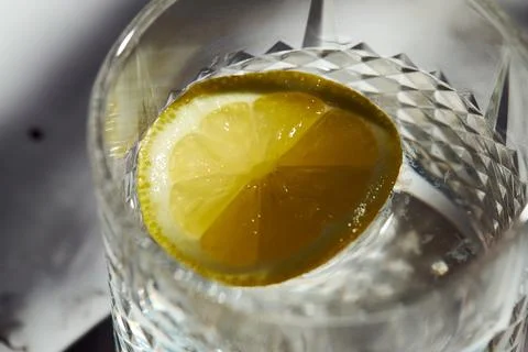 Close-up of a fresh lemon slice floating in a crystal glass of water Stock Photos
