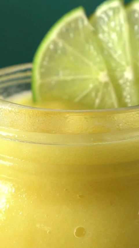 Close-up of fresh mango juice with lime slices, bright yellow tropical drink and Stock Footage 347177594