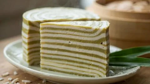 Close-up of a fresh matcha sponge cake with white cream layers, sliced and Stock Photos