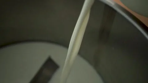 A close-up of fresh milk being transferred from a container to a stainless steel Stock Footage 281430366