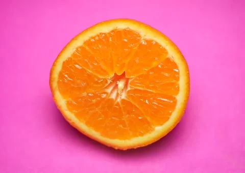 Close up of fresh orange fruit texture on vibrant pink background Stock Photos