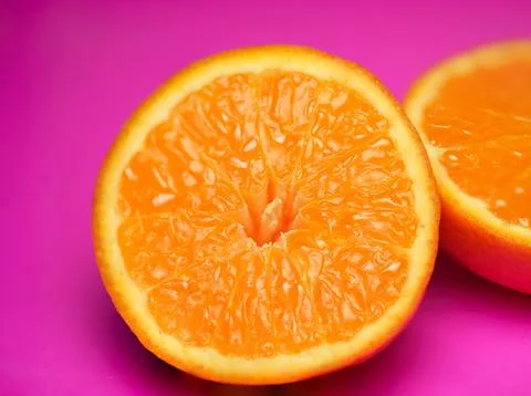 Close up of fresh orange fruit texture on vibrant pink background Stock Photos