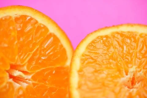 Close up of fresh orange fruit texture on vibrant pink background Stock Photos