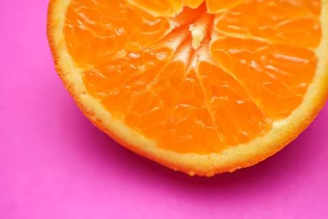 Close up of fresh orange fruit texture on vibrant pink background Stock Photos