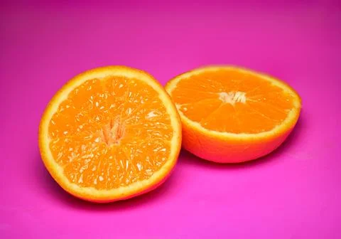 Close up of fresh orange fruit texture on vibrant pink background Stock Photos