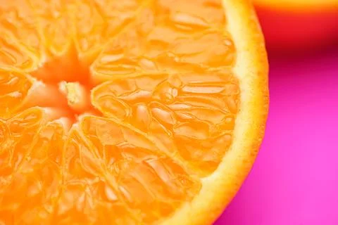 Close up of fresh orange fruit texture on vibrant pink background Stock Photos