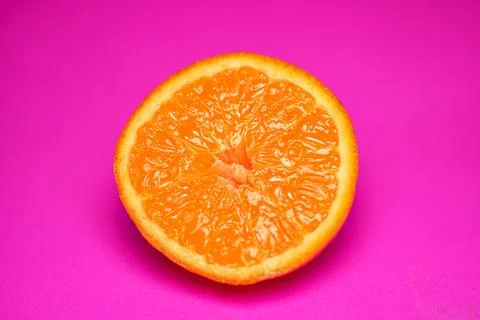 Close up of fresh orange fruit texture on vibrant pink background Stock Photos