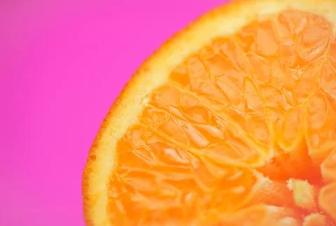 Close up of fresh orange fruit texture on vibrant pink background Stock Photos