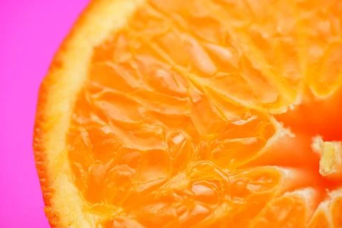 Close up of fresh orange fruit texture on vibrant pink background Stock Photos